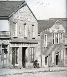 An old photo of a main street with stores, one store's sign reads "Auction & Negro Sales."