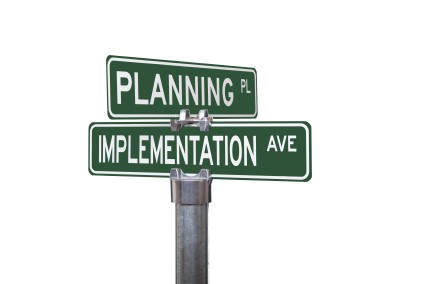 Two intersecting road signs reading "Planning" and "Implementation"