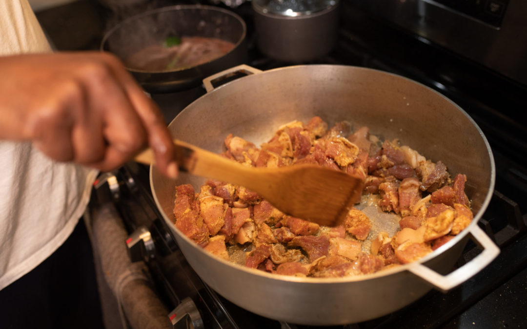 A pot of seasoned meat simmers on a stove