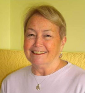 Headshot of Julie Beckett, wearing a light purple shirt and a gold necklace.