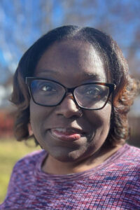Photo of Dr. Allysa Ware, Executive Director of Family Voices. She is a Black woman with brown, curly hair and glasses. 