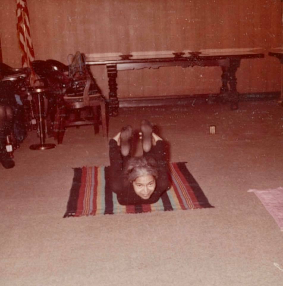 Rosa parks holds a yoga pose on a colorful mat.