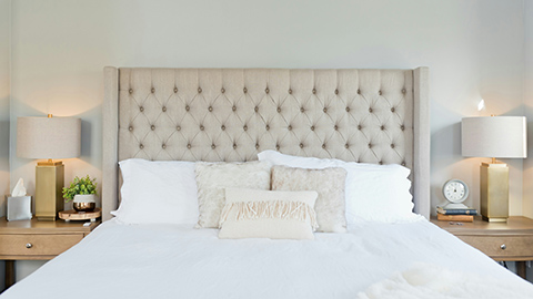 An empty bed with white bedding and white pillows.